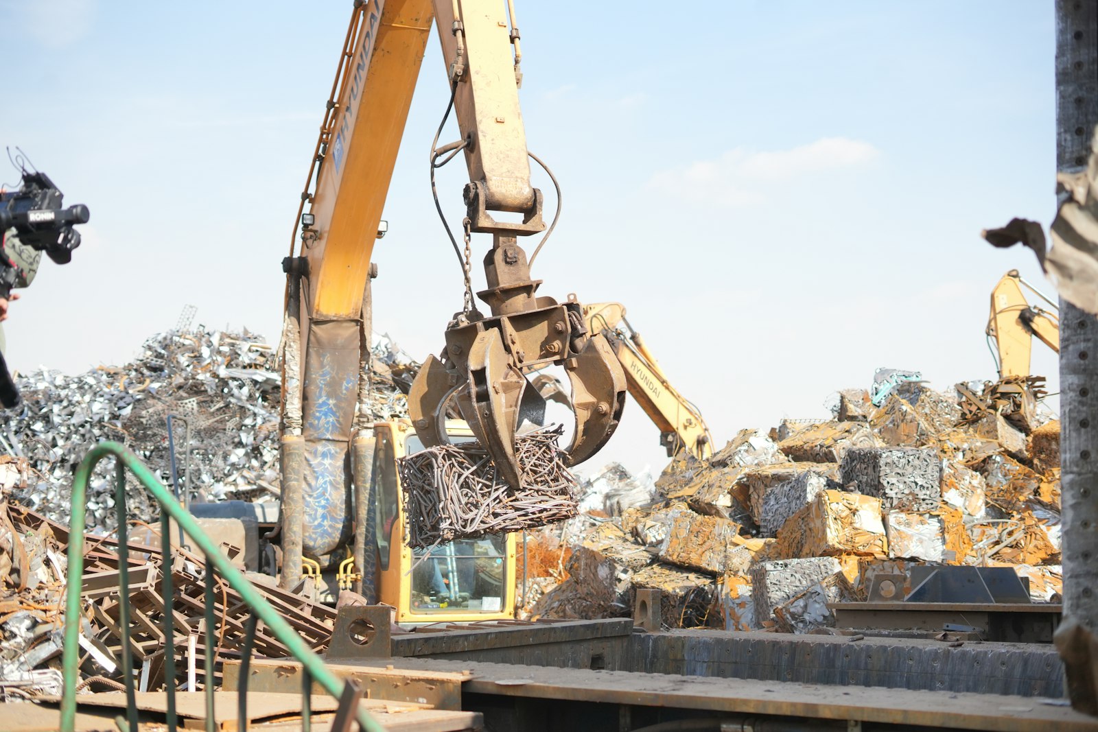 Excavator working on a large pile of scrap metal at a recycling yard